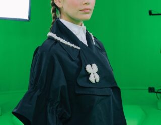 Young model in black blazer with white pearl accessories