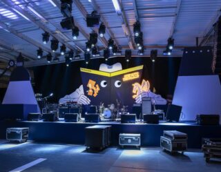 Event stage setup with illustrated book backdrop and production lighting rigs
