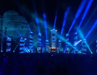 Concert stage with dramatic blue lighting and projection screens
