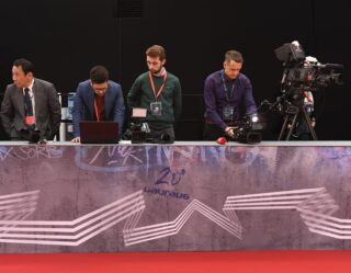 Panel of four men at Laureus event with camera