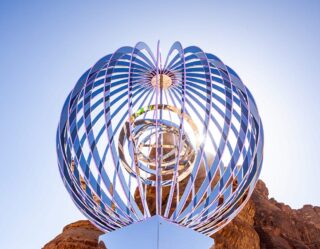 Large blue spherical metal sculpture against clear sky