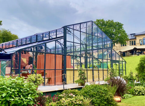 Bespoke glass greenhouse event structure set in a landscaped garden