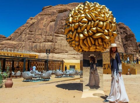 Giant golden brain sculpture in desert landscape with ancient rock formations