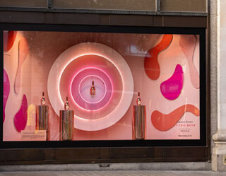 Luxury perfume store window display with neon pink circles