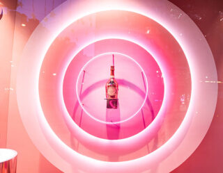Pink neon circular rings displaying perfume bottle