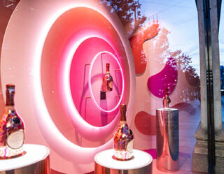 Pink neon circular display with luxury perfume bottles