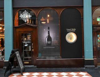 Elegant storefront with turquoise facade and wine display