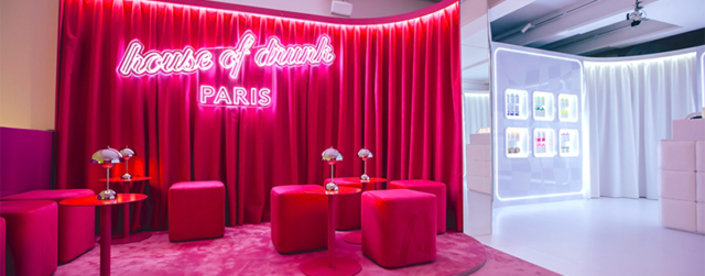 Pink pop-up lounge with neon signage, velvet seating, and red curtain backdrop